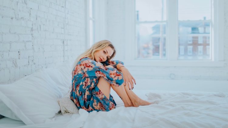 Woman Wearing Floral Dress While Sitting On Bed Cute Spring Dresses That Will Make You Stand Out | Featured