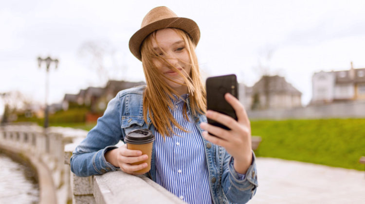 Woman holding cup while taking selfie | Easy Ways to Perfect Your #OOTD Selfie Poses | holding the camera | Featured