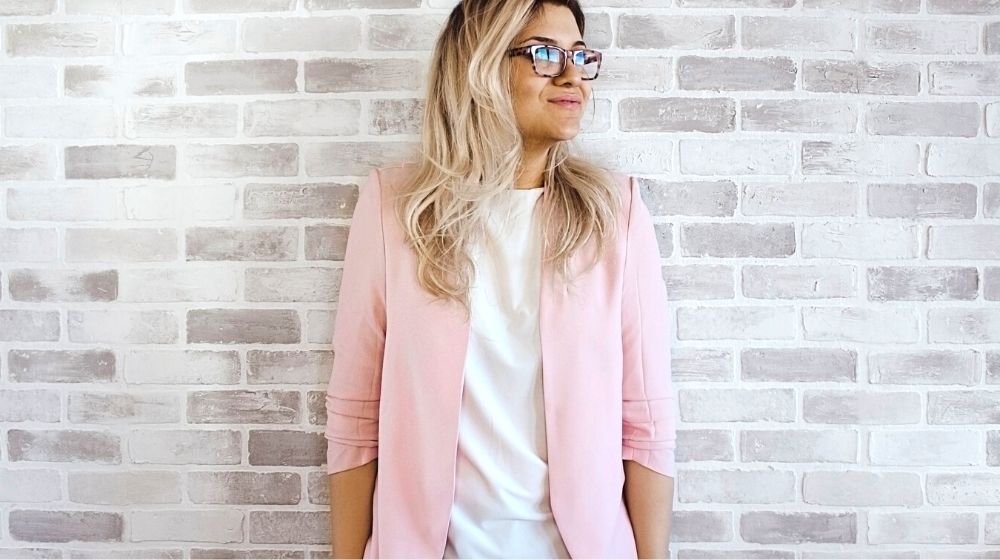 woman in pink cardigan and white shirt leaning on the wall | Cute Fall Work Outfit Ideas To Make You Stand Out in the Office