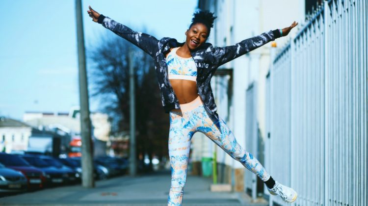 woman happy dancing at the street wearing athleisure fashion | 12 Athleisure Brands You Should Check Out | FEATURED