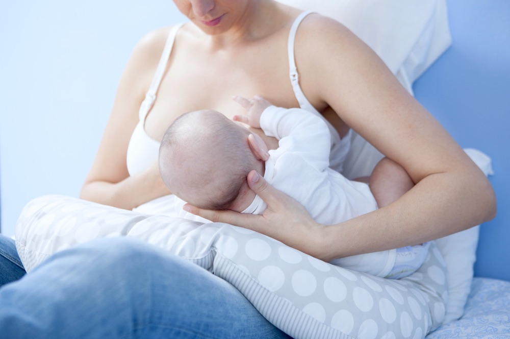 Woman Nursing Child On Bed | Comfortable Breastfeeding Clothes You Can Wear Everyday