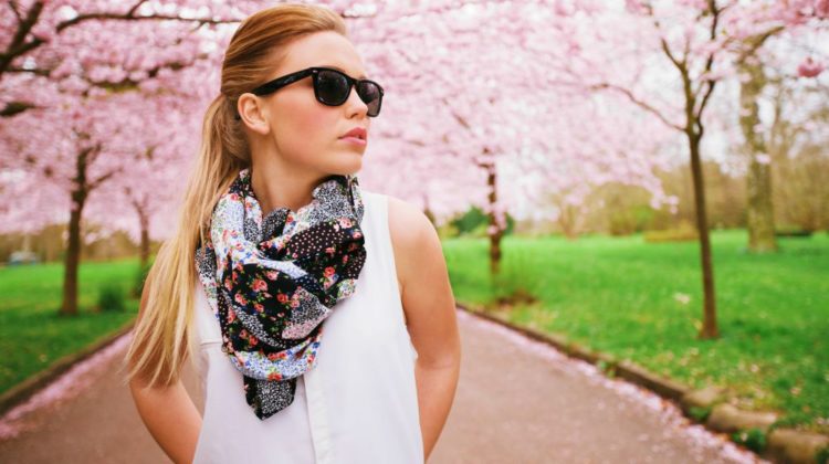 Pretty caucasian female model standing outdoors at a park wearing sunglasses and scarf looking away | Lightweight Spring Scarves and Ways to Use it | spring silk scarves | Featured