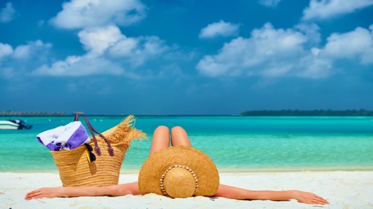 Woman lying down on beach | Hottest Straw Bags Worth Buying This Summer | straw summer bag | Featured