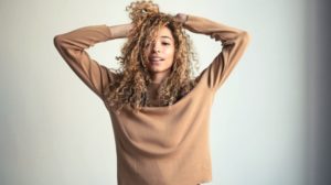 happy young lady holding her curly hair | Cute Curly Hairstyles You'll Surely Fall In Love With | Featured