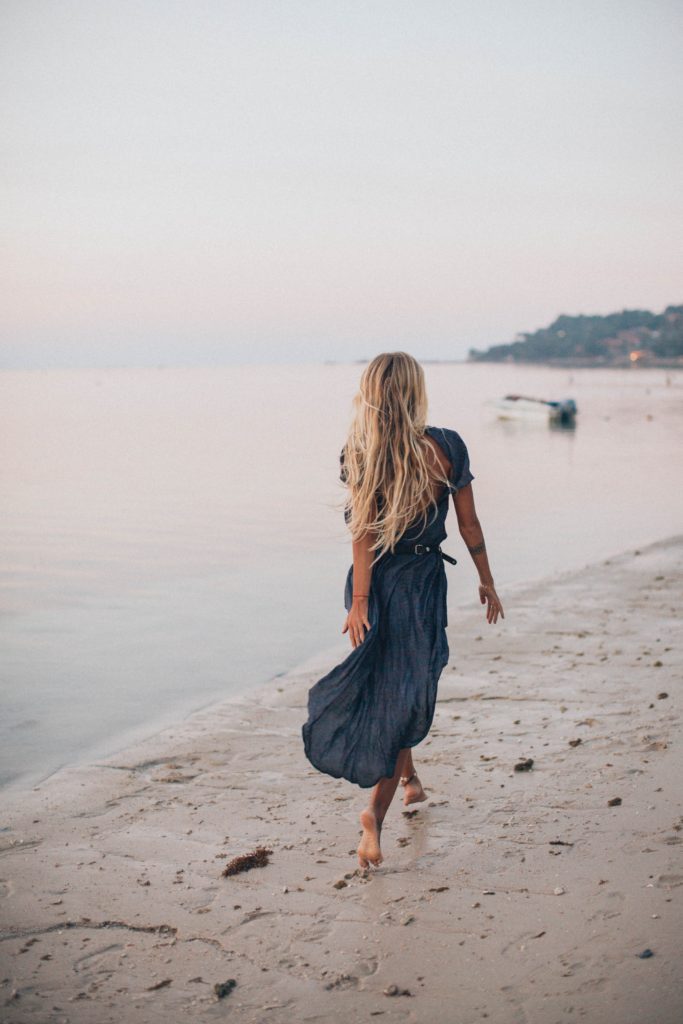 photo of woman walking on seashore | Stylish Beach Outfits That Arent Just Swimsuits and Sunglasses | beach outfits | Featured