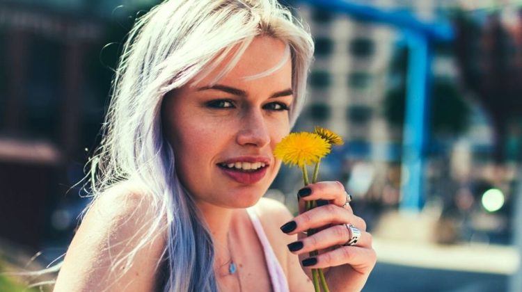 grey haired young lady holding yellow flowers | Best Purple Shampoo To Brighten Grey Hair | Featured