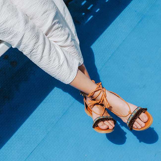 woman wearing white pants and tassled strappy sandals | Strappy Sandals For Your Cute Laidback Outfits
