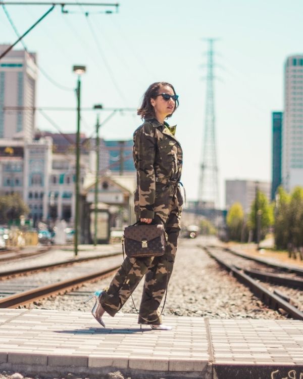 Stylish lady holding a handbag waring a camo jumpsuit | Reasons To Embrace The Utility Jumpsuit Trend