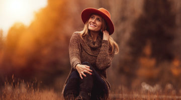 woman sitting on grass field and smiling | Ways To Pull Off Fall Hats This Season | Featured
